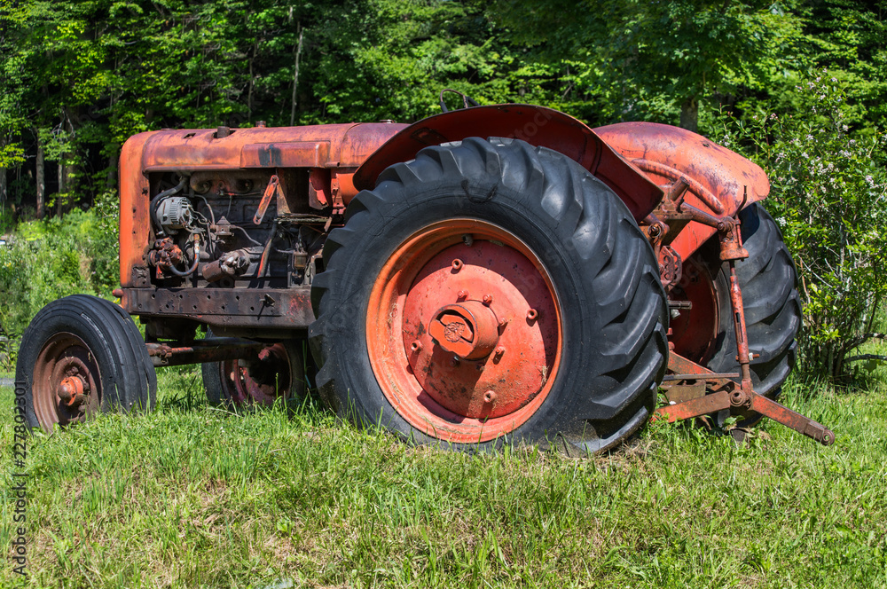 Old unused tractor in grass field Old unused tractor in grass field