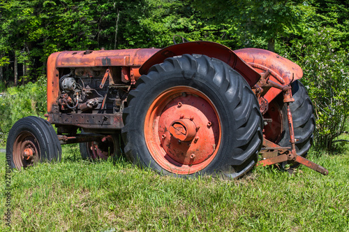 Old unused tractor in grass field