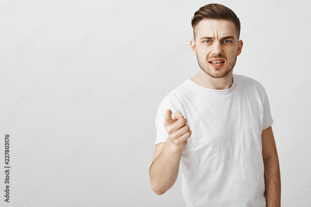 Pissed serious-looking boyfriend blaming friend pointing at camera with index finger and frowning arguing over gray background being set up by coworker standing displeased and disappointed Pissed serious-looking boyfriend blaming friend pointing at camera with index finger and frowning arguing over gray background being set up by coworker standing displeased and disappointed