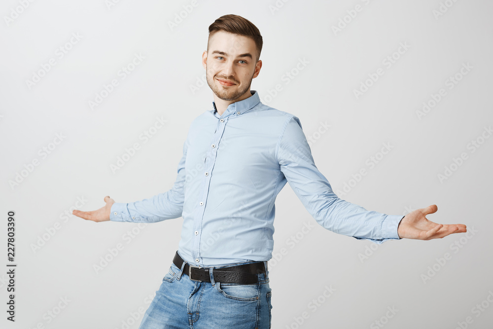 Praise me I am awesome. Portrait of confident delighted successful handsome guy with bristle spreading palms aside and smiling with self-assured pose knowing he is smart and skillful over gray wall Praise me I am awesome. Portrait of confident delighted successful handsome guy with bristle spreading palms aside and smiling with self-assured pose knowing he is smart and skillful over gray wall