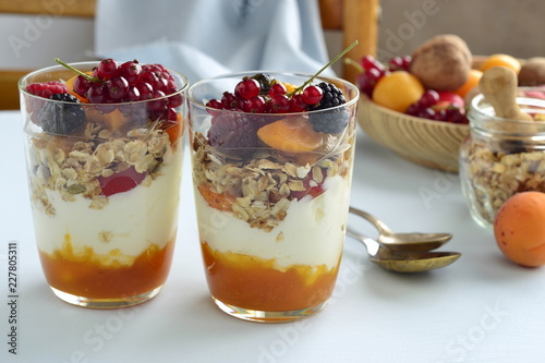 Dessert with cream, jam, muesli and fresh berries in a glass