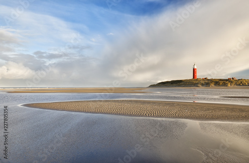 high tide on beach by red lighthouse