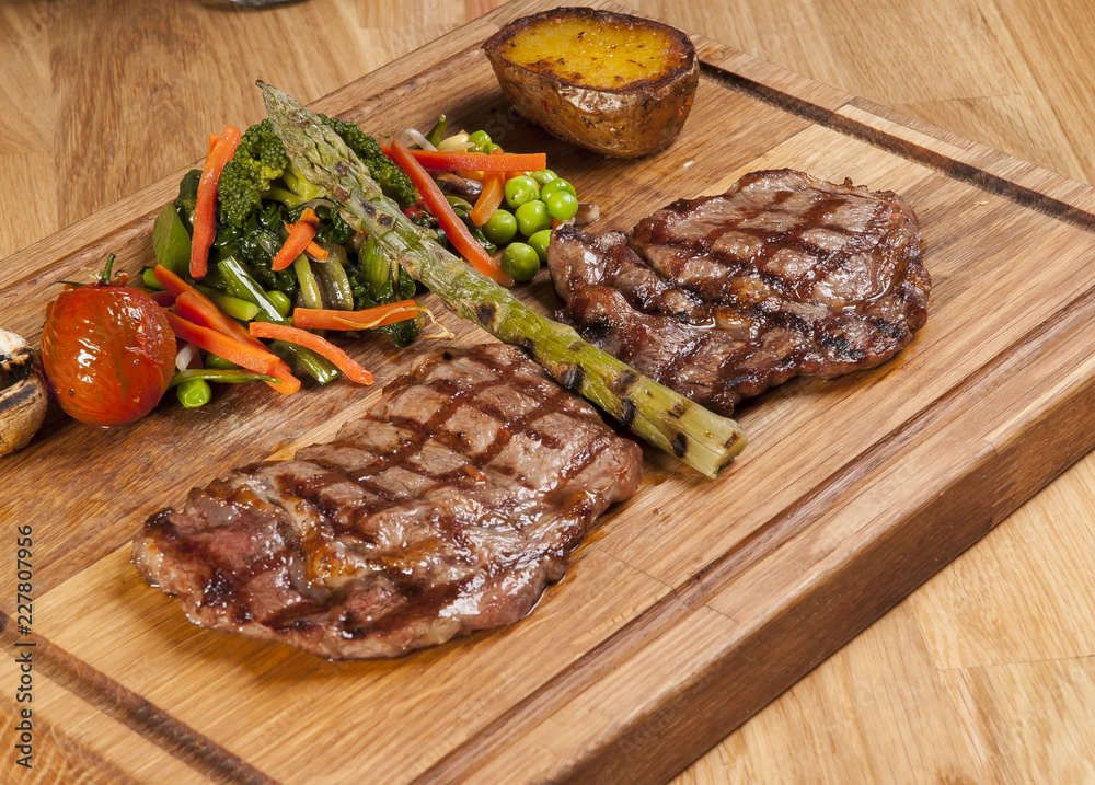 Meat steak on the wooden board with vegetables Meat steak on the wooden board with vegetables