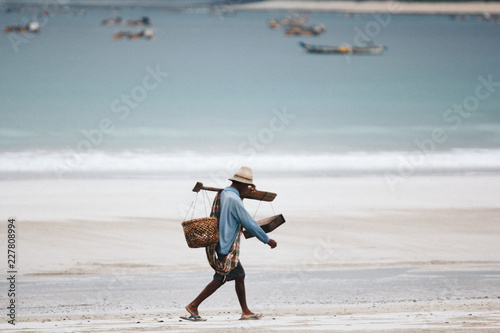 man carrying fish on the beach