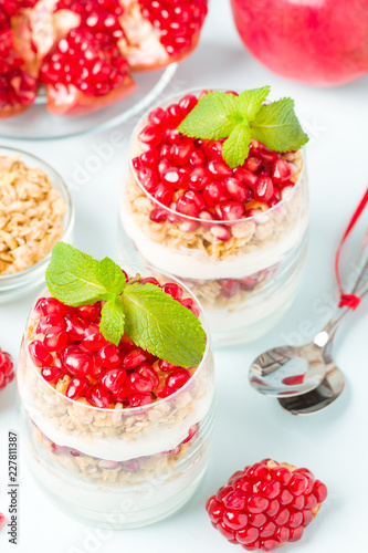 Pomegranate parfait - sweet organic layered dessert with granola flakes  yogurt and red ripe fruit seeds.