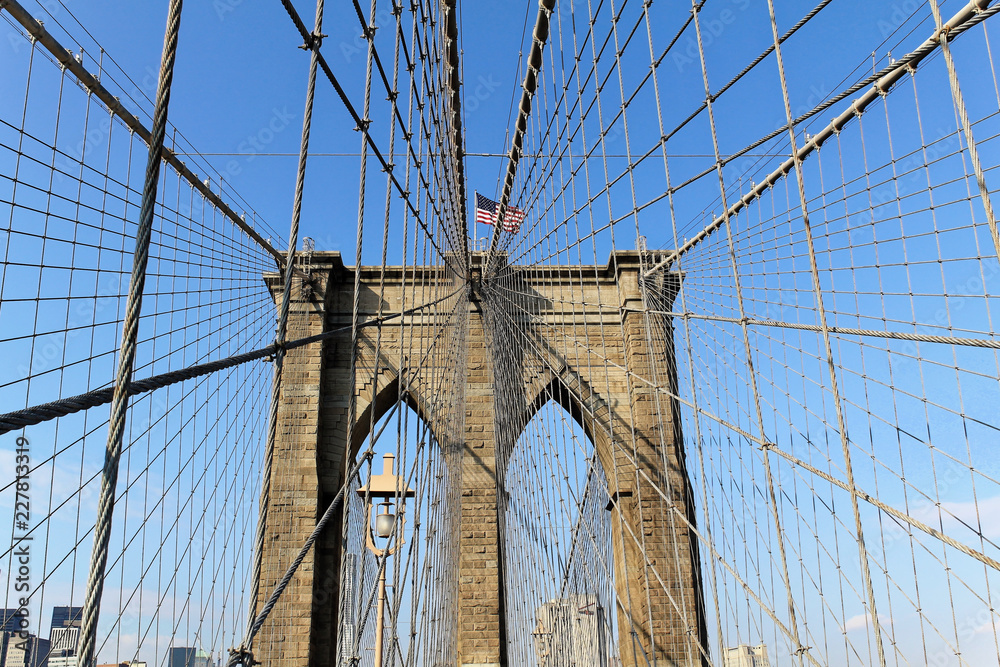 Fototapeta premium New York, USA - November 22, 2010: The historic Brooklyn Bridge in New York City with US flag