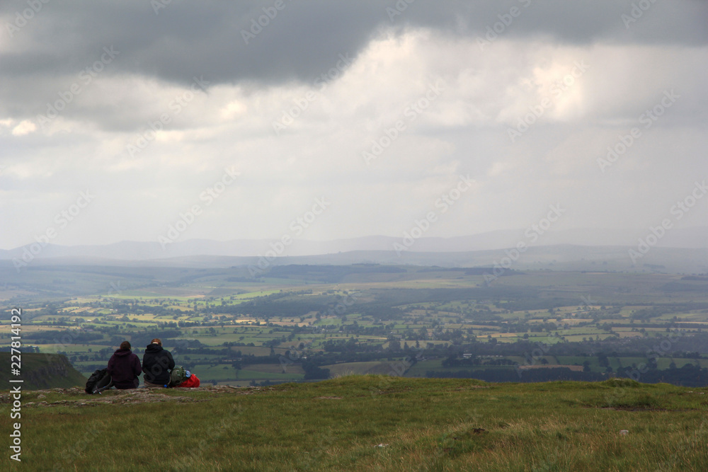 A pair of hikers sit down for lunch at the edge of High Cup Nick in the Pennines on a typical English summer’s day