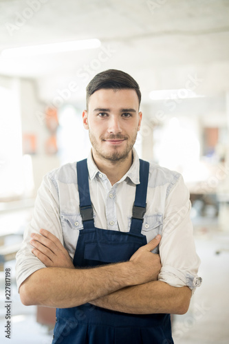 Young confident cross-armed man in workwear standing in his workshop