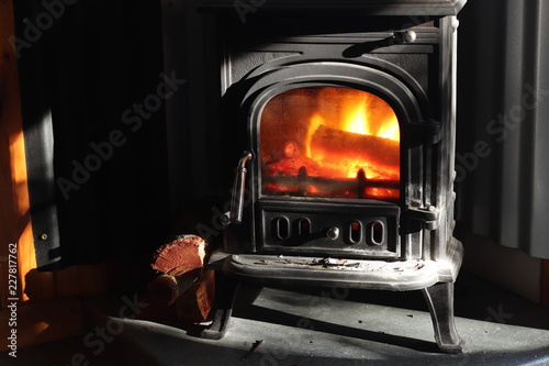 Bilde på lerret A black cast iron fire place with wood burning inside of it