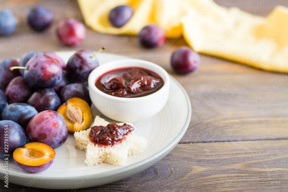 Appetizing bruschetta from fresh bread with plum jam and ripe berries of blue plums on a plate on a wooden table Appetizing bruschetta from fresh bread with plum jam and ripe berries of blue plums on a plate on a wooden table