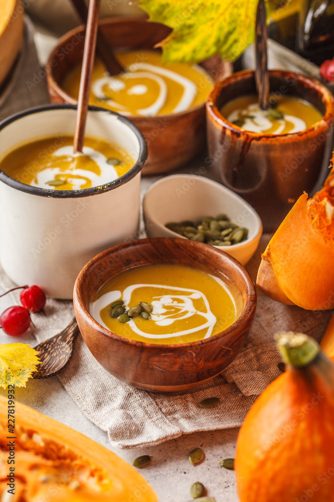 Autumn pumpkin soup puree with cream in cups, the autumn scenery. Healthy vegan food concept.