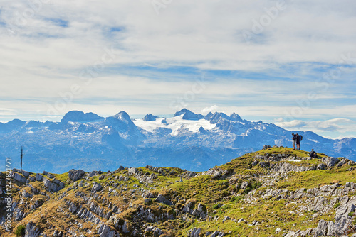Three young people sit on a berg and look at the Smartphone. Salzkammergut, region, Alps, Austria. photo