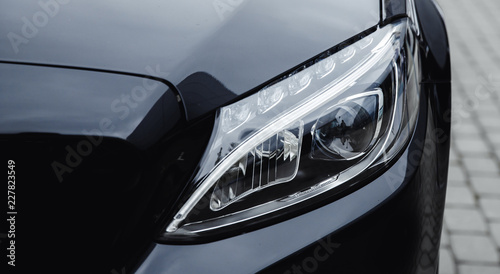 Closeup headlight luxury sedan car lighting road.