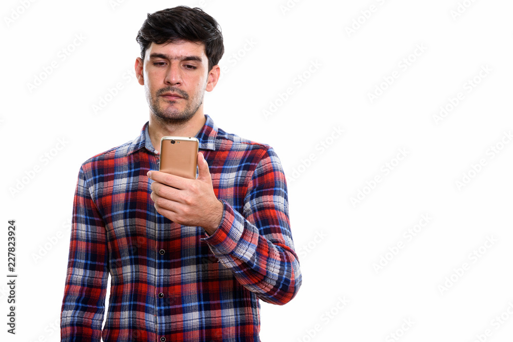 Studio shot of young Persian man using mobile phone
