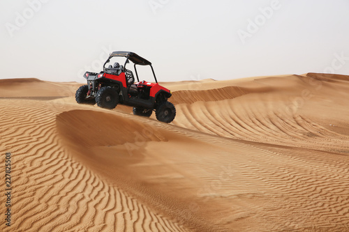 Off-road SUV vehicle speeding through sand dunes in the Arabian desert.