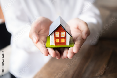 Female real estate agent hand holding house model, Real estate concept.