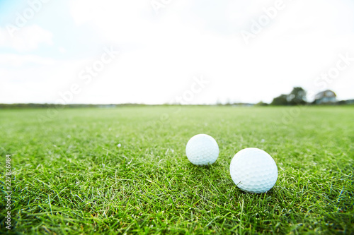 Two golf balls on green grass of vast play field in natural environment