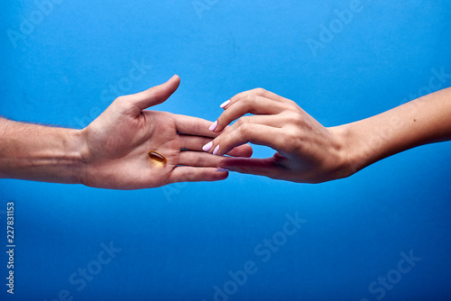 A male doctor gives a female Viagra to a female patient. The guy gives the girl a drug, medicine, vitamin, fish oil in a transparent capsule. The boy passes the pill to the girl.