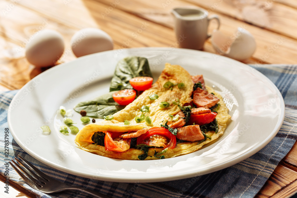 Herb omelette with chives, cherry tomatoes and spinach on wooden table under sunlight. Healthy breakfast concept Herb omelette with chives, cherry tomatoes and spinach on wooden table under sunlight. Healthy breakfast concept