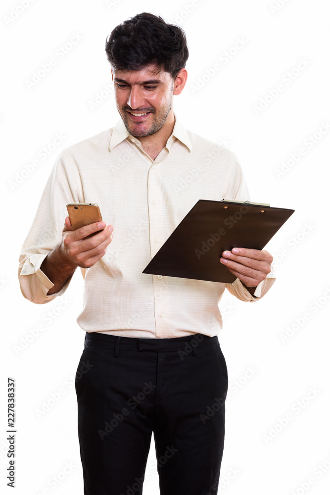 Young happy Persian businessman smiling and holding clipboard wh