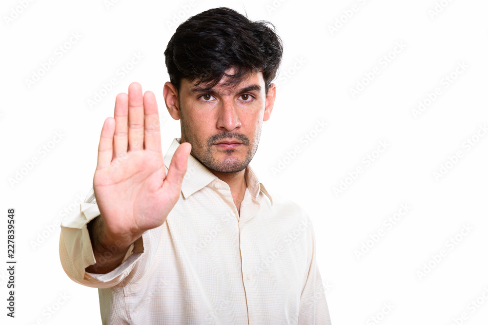 Studio shot of young Persian businessman with stop hand gesture Studio shot of young Persian businessman with stop hand gesture