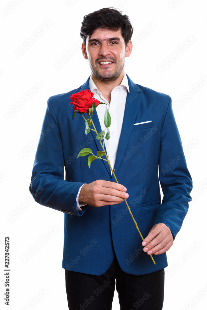 Studio shot of young happy Persian businessman smiling while hol Studio shot of young happy Persian businessman smiling while hol