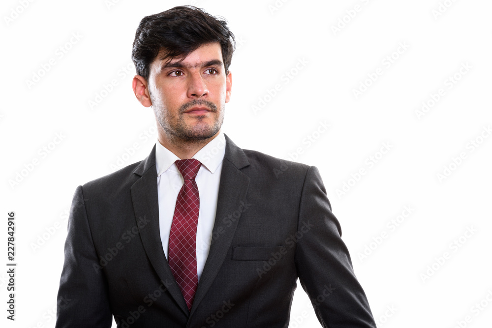 Studio shot of young Persian businessman thinking while looking Studio shot of young Persian businessman thinking while looking