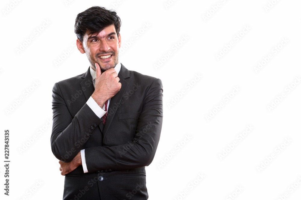 Studio shot of young happy Persian businessman smiling while thi Studio shot of young happy Persian businessman smiling while thi