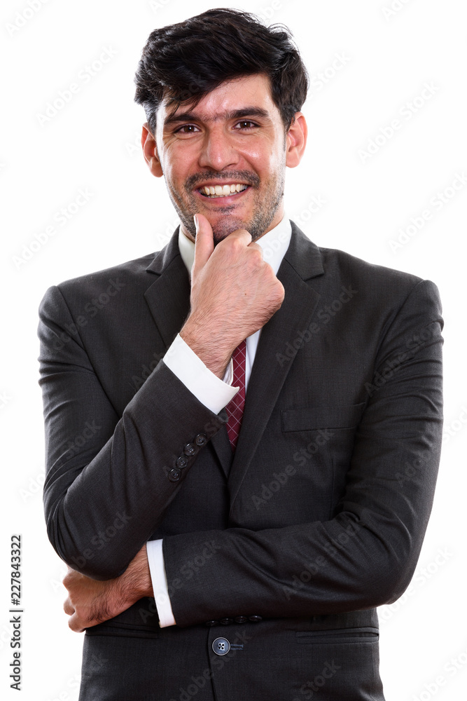 Studio shot of young happy Persian businessman smiling while thi Studio shot of young happy Persian businessman smiling while thi