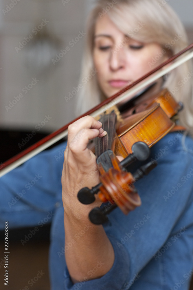 Young beautiful woman violin player looking at camera over instrument on her shoulder holding bow. Young beautiful woman violin player looking at camera over instrument on her shoulder holding bow.