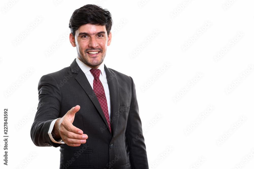 Studio shot of young happy Persian businessman smiling while giv Studio shot of young happy Persian businessman smiling while giv