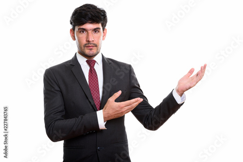 Studio shot of young Persian businessman showing something