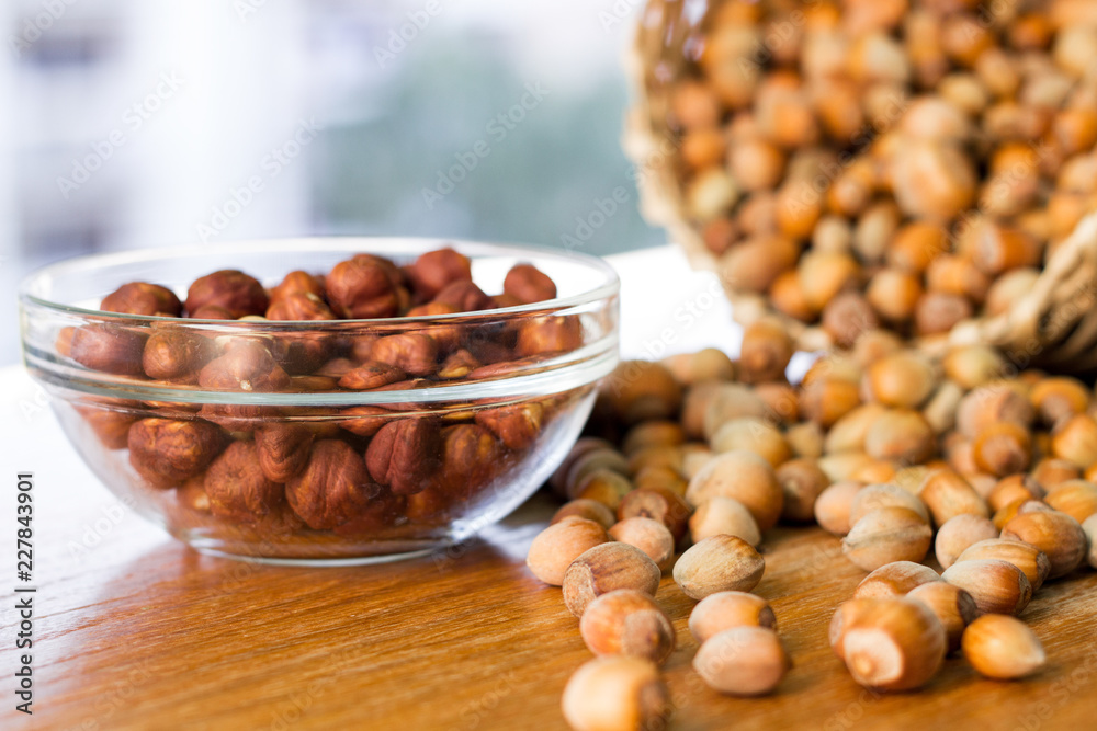 Obraz premium Hazelnuts in a wicker basket on old wooden table 