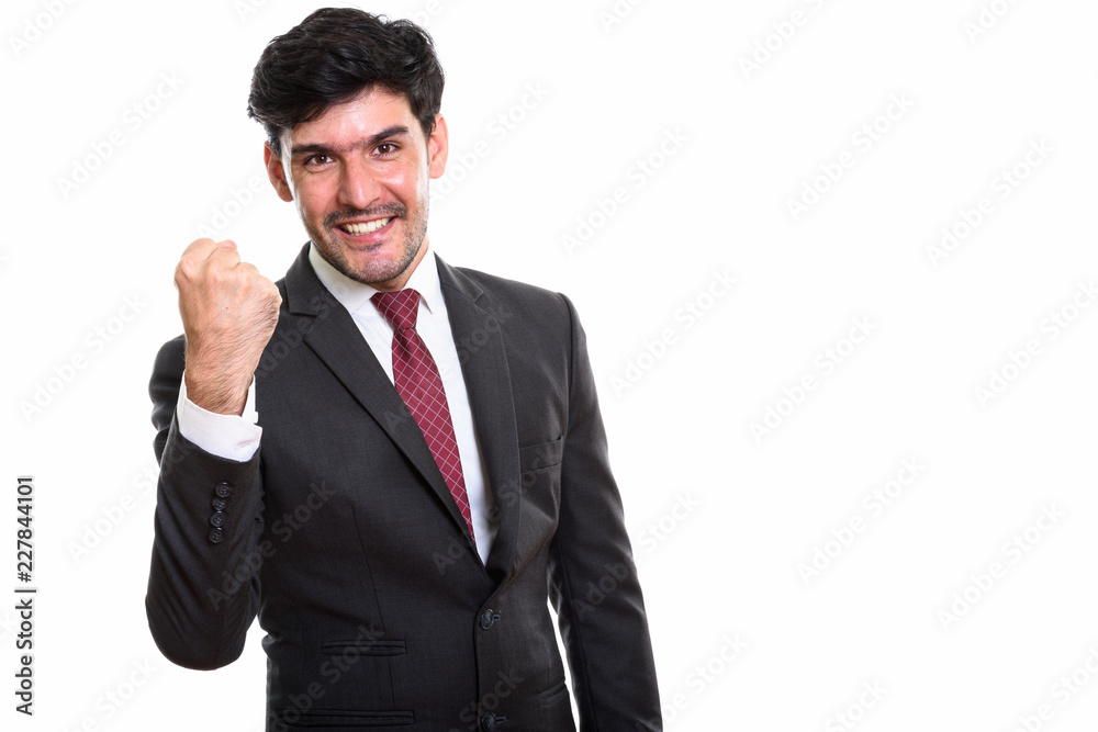 Studio shot of young happy Persian businessman smiling while loo Studio shot of young happy Persian businessman smiling while loo