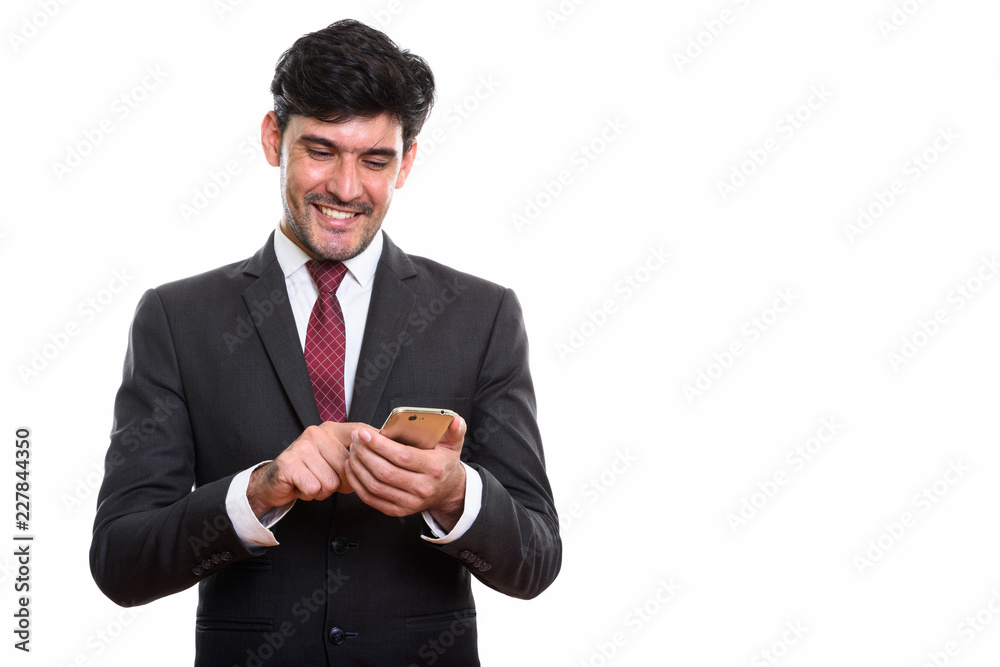 Studio shot of young happy Persian businessman smiling while usi Studio shot of young happy Persian businessman smiling while usi
