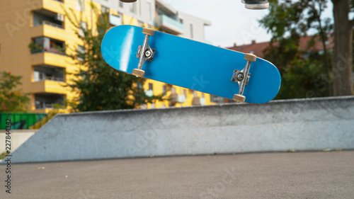 Fotografie CLOSE UP: Young male skateboarder lands a varial kickflip on a sunny fall day