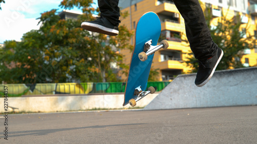 Fotografie CLOSE UP: Unrecognizable man on skateboard does a cool flip trick at the park
