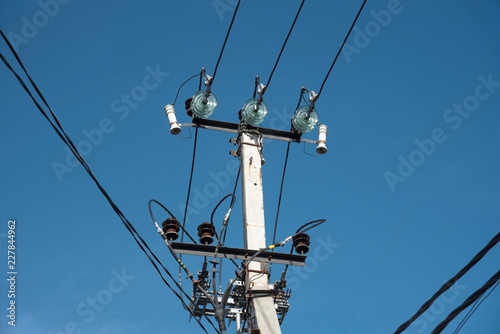 pole with electrical and telephone wires against the blue sky. internet cable light guide. electricity on a concrete pole
