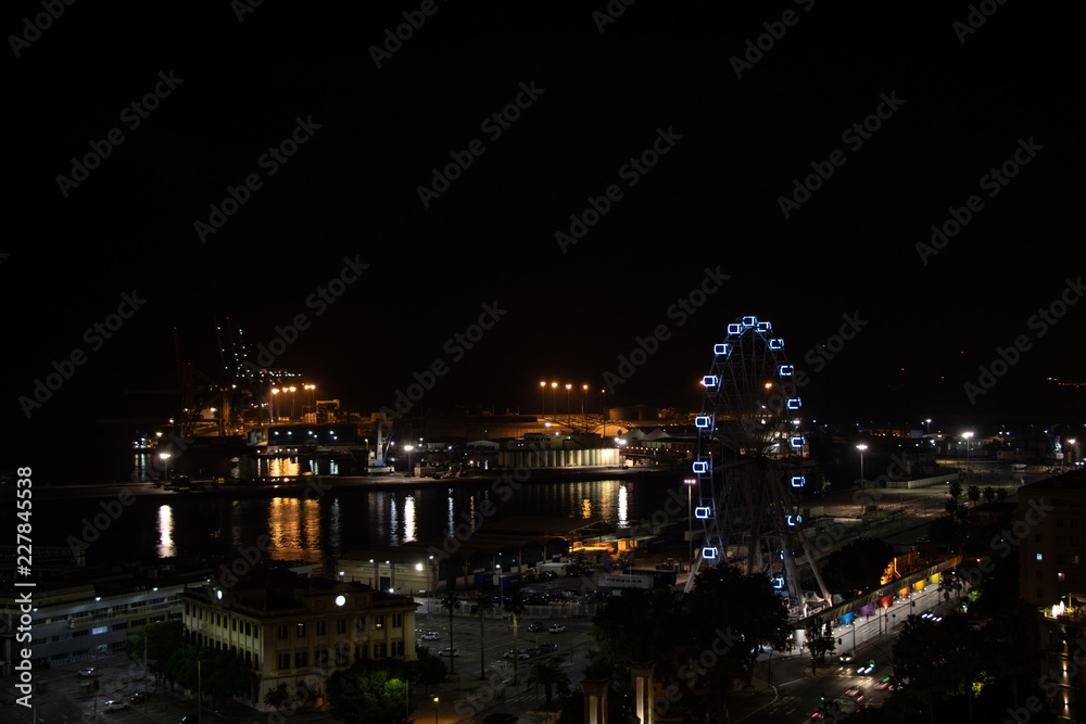 Night view of a city with the port and a ferris wheel. Malaga, Spain