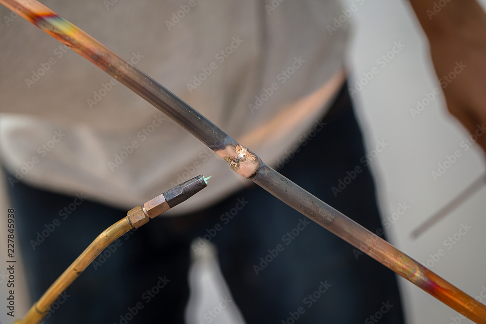 Naklejka premium Welding of copper pipe of a methane gas pipeline or of a conditioning or water system. Welding soldering copper pipes. Gas Welding Pipe brass contractor air con mechanic Outdoors.