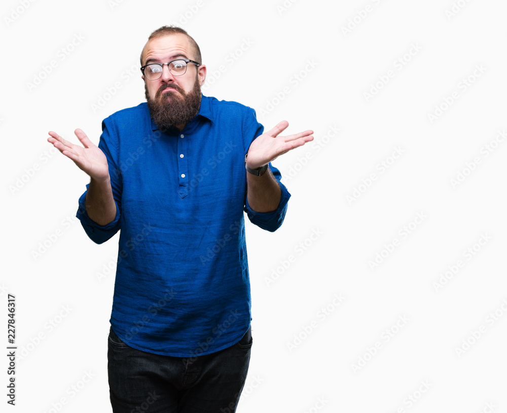 Fototapeta premium Young caucasian hipster man wearing glasses over isolated background clueless and confused expression with arms and hands raised. Doubt concept.
