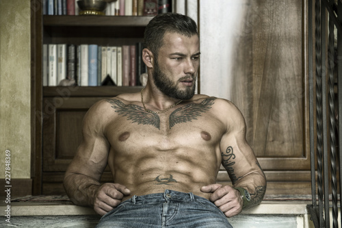 Photo Portrait of sexy shirtless muscular man sitting on stair steps during the day, w