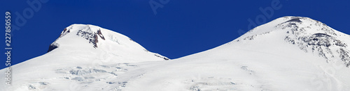 Panoramic view of the southern slope of Mount Elbrus of the Caucasus Mountains in Russia. Snow-covered mountain peaks with two peaks. © olgapkurguzova