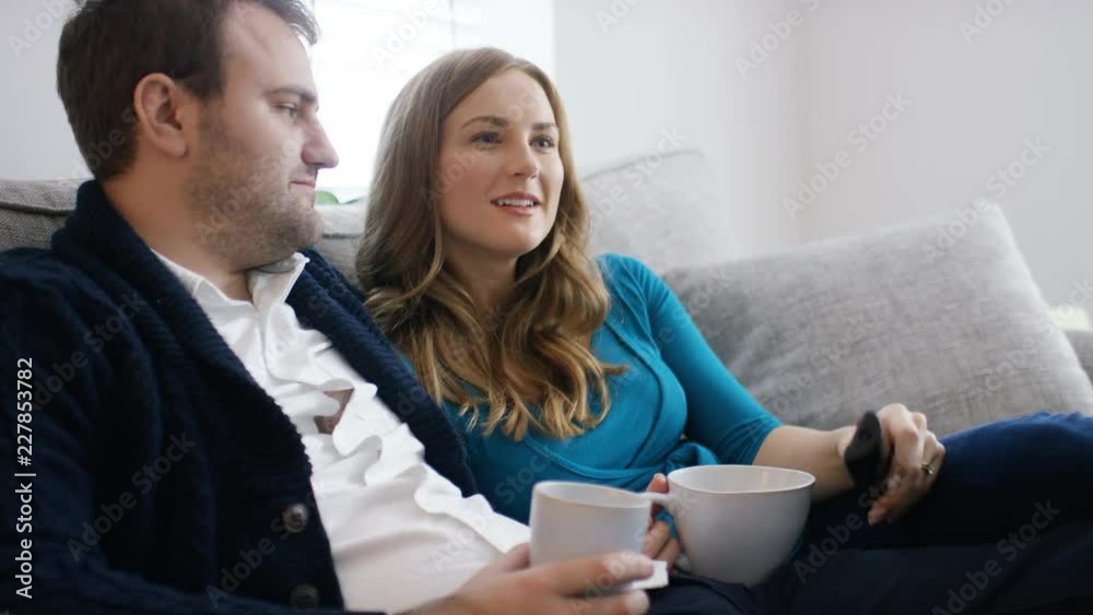 Young couple at home flick through television channels with remote control Young couple at home flick through television channels with remote control