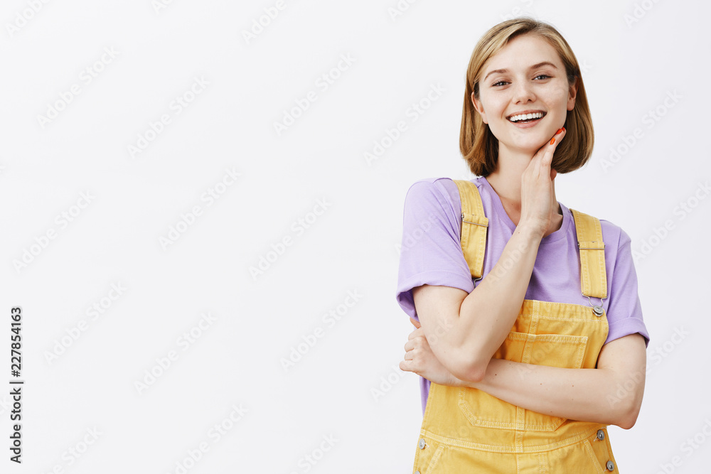 Good-looking pleased confident woman with blond short haircut, touching neck gently and smiling with proud and self-assured expression at camera, being master in painting and gazing at own masterpiece Good-looking pleased confident woman with blond short haircut, touching neck gently and smiling with proud and self-assured expression at camera, being master in painting and gazing at own masterpiece
