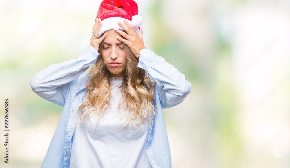 Beautiful young blonde woman wearing christmas hat over isolated background suffering from headache desperate and stressed because pain and migraine. Hands on head. Beautiful young blonde woman wearing christmas hat over isolated background suffering from headache desperate and stressed because pain and migraine. Hands on head.