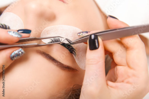 Eyelash Extension Procedure. Woman Eye with Long Eyelashes. Close up  selective focus.