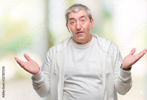 Handsome senior man wearing sport clothes over isolated background clueless and confused expression with arms and hands raised. Doubt concept.