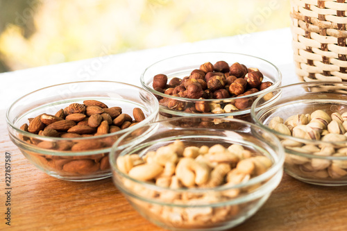 Assortment of mixed nuts and wicker basket on wood table background