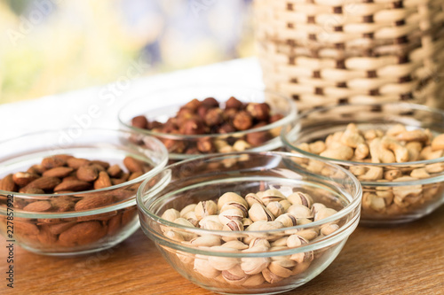 Assortment of mixed nuts and wicker basket on wood table background